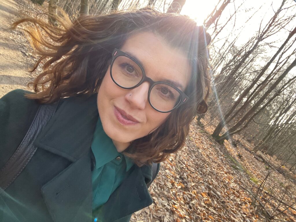 Victoria the celebrant wearing a green coat walking through woodland